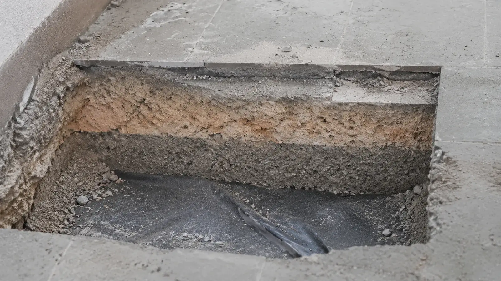 Saggio esplorativo su un solaio: porzione di massetto rimossa che mostra la stratigrafia e la guaina impermeabilizzante