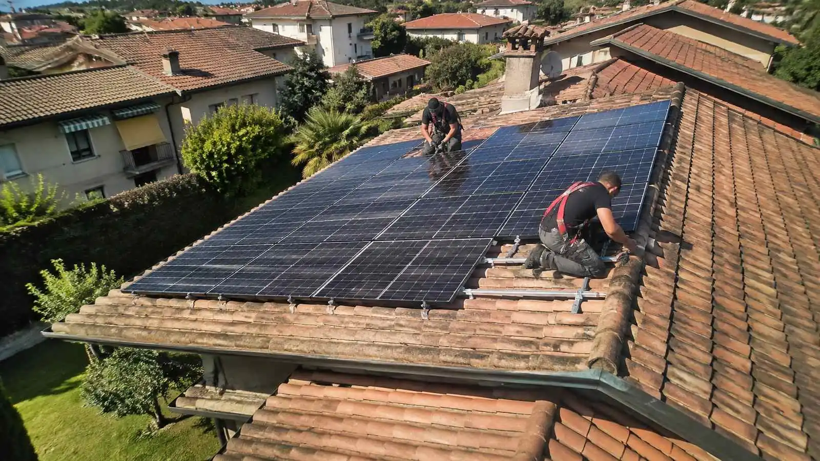 Tetto a falda in tegole con moduli fotovoltaici installati e staffe di fissaggio in vista, fotografato dall'alto in una giornata limpida