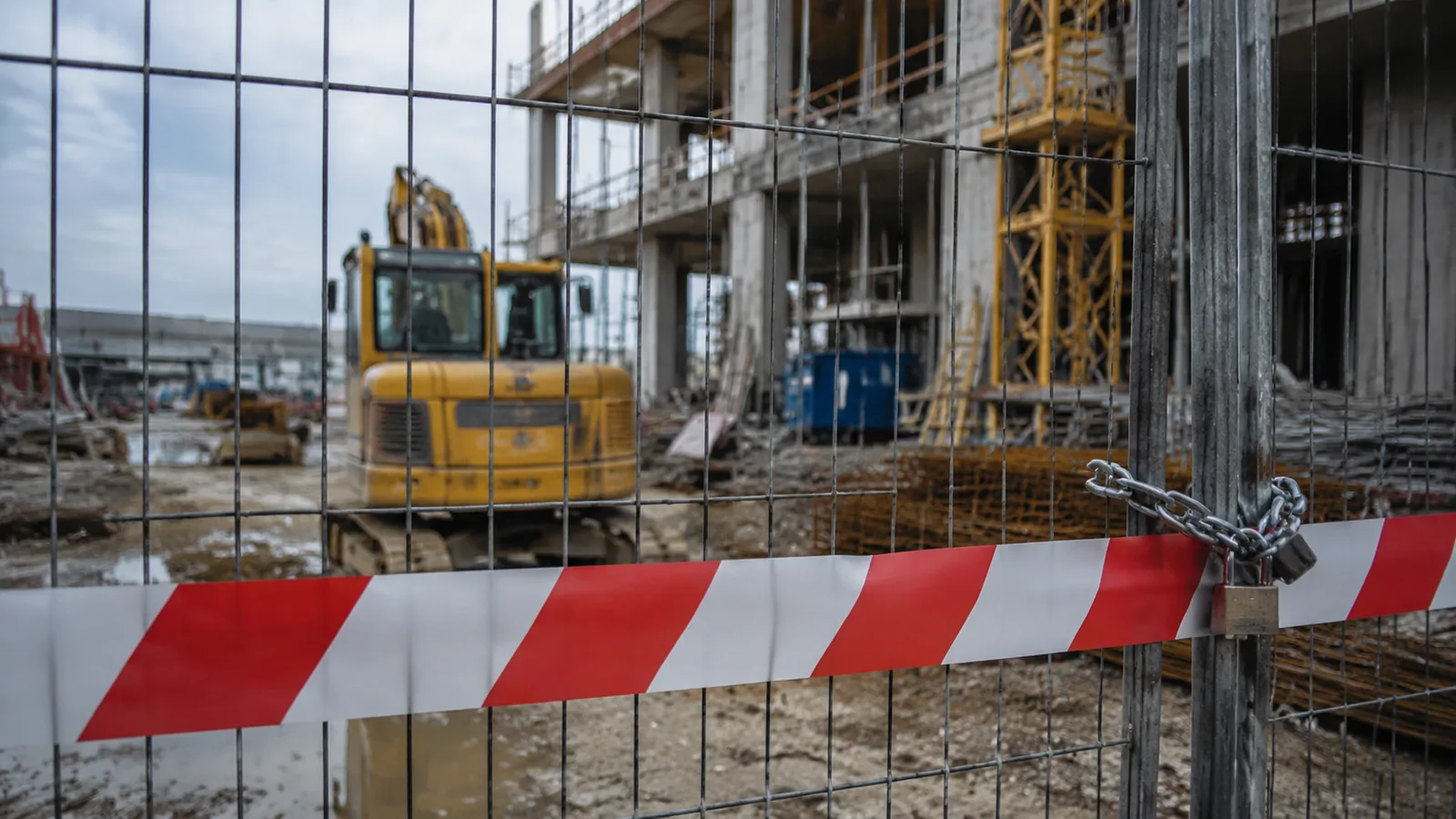 Cantiere fermo con nastro di delimitazione e mezzi inattivi