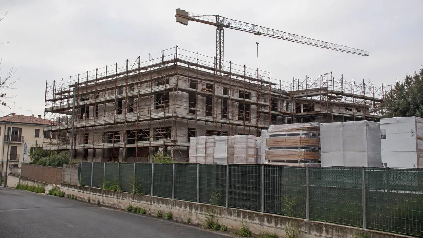 Cantiere fermo con gru immobile e ponteggi montati, nessun operaio al lavoro