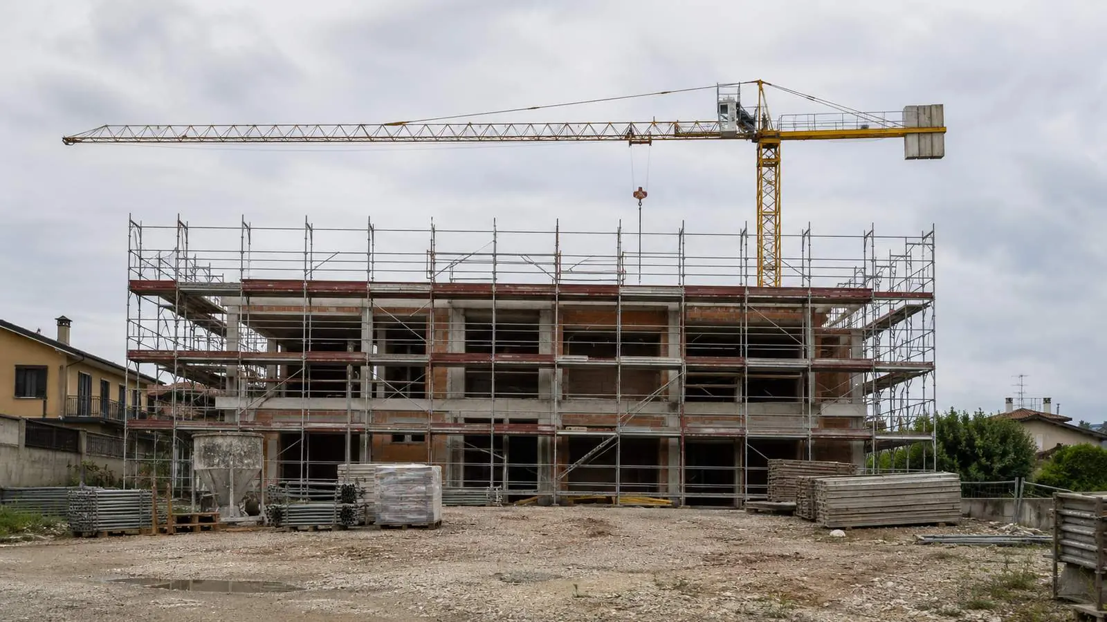 Cantiere fermo con gru immobile e ponteggi montati, nessun operaio al lavoro